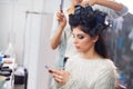 Taking care of business in the stylists chair. A young model at the hair salon having her done while checking her phone. Royalty Free Stock Photo