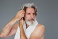 Taking care of face and skin clearness. Stylish modern senior man with gray hair and beard is indoors