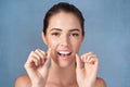 Taking care of her pearly whites. Studio portrait of an attractive young woman flossing her teeth against a grey Royalty Free Stock Photo