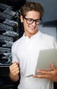 Taking care of your network needs. A technician in a server room looking at a laptop.