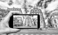 Taking colors out of black and white. Female hand with smartphone taking a picture of Paris. Tourism concept