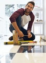 Taking on this DIY project one tile at a time. Portrait of a smiling man laying floor tiles. Royalty Free Stock Photo