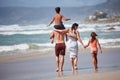 Taking a family beach stroll. Rearview shot of a family walking along the beach.