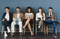 Taking the first step to a new career. Studio shot of a group of businesspeople using wireless technology while waiting Royalty Free Stock Photo