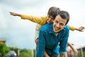 Taking flight with my little man. Portrait of a cheerful young father giving his son a piggyback ride outdoors. Royalty Free Stock Photo