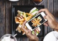 Taking food photo, food photography by smart phone, club sandwich with french fries on wooden table Royalty Free Stock Photo