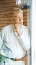 Taking a moment to think it over...a contemplative senior man looking out from his bedroom window. Royalty Free Stock Photo