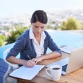 Taking notes. a young businesswoman working on her laptop by a swimming pool. Royalty Free Stock Photo