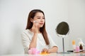 Taking off her make-up. Beautiful cheerful young woman using cotton disk and looking at her reflection in mirror with smile while Royalty Free Stock Photo