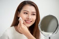 Taking off her make-up. Beautiful cheerful young woman using cotton disk and looking at her reflection in mirror with smile while Royalty Free Stock Photo