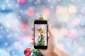 Taking photo of Christmas star on Christmas tree by mobile smart phone, Snow with Bokeh lights background Royalty Free Stock Photo