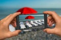 Taking photo of sunbathing beds and red umbrella with phone Royalty Free Stock Photo