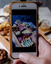 Taking photograph of food served on the table with your smartphone. Charcuterie. Picada Argentina Royalty Free Stock Photo