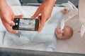 Taking picture by smartphone. Father with his newborn baby is indoors. Conception of single dad Royalty Free Stock Photo