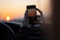 Taking pictures of sunset with smartphone through car window Royalty Free Stock Photo