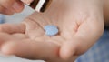 Two big blue diamond-shaped pills labeled 100 fall into palm of hand from pill bottle. Close-up, front view, center Royalty Free Stock Photo