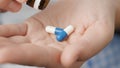 Two big white-blue cylindrical capsule pills fall into palm of hand from pill bottle. Close-up, front view, center Royalty Free Stock Photo