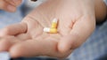 Two big white-yellow cylindrical capsule pills fall into palm of hand from pill bottle. Close-up, front view, center Royalty Free Stock Photo