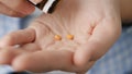 Two small orange round pills fall into palm of hand from pill bottle. Close-up, front view, center composition Royalty Free Stock Photo