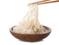 Taking rice noodles with chopsticks from bowl on white