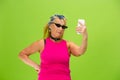 Senior woman in ultra trendy attire isolated on bright green background