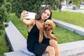 Pretty girl and her pet, little golden poodle dog strolling in public park, outdoors. Summer time. Sincere emotions Royalty Free Stock Photo