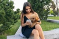 Pretty girl and her pet, little golden poodle dog strolling in public park, outdoors. Summer time. Sincere emotions Royalty Free Stock Photo