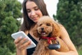 Pretty girl and her pet, little golden poodle dog strolling in public park, outdoors. Summer time. Sincere emotions Royalty Free Stock Photo