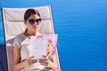 Taking some down time. An attractive young woman reading a magazine while lying on a deck chair. Royalty Free Stock Photo