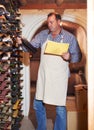 Taking stock. A mature man doing a wine stock take in his cellar.