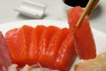 Taking tasty salmon slice with chopsticks from plate, closeup. Delicious sashimi dish