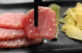 Taking tasty sashimi (piece of fresh raw tuna) from black plate, closeup