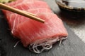 Taking tasty sashimi (pieces of fresh raw tuna) from black board, closeup