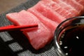 Taking tasty sashimi (pieces of fresh raw tuna) from plate, closeup