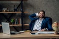 Taking time for a minute break. Cheerful young man holding hands behind head and keeping eyes closed while sitting at his working Royalty Free Stock Photo