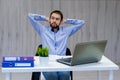 Taking time for a minute break. Cheerful young man holding hands behind head and keeping eyes closed while sitting at his working Royalty Free Stock Photo