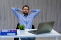 Taking time for a minute break. Cheerful young man holding hands behind head and keeping eyes closed while sitting at his working Royalty Free Stock Photo