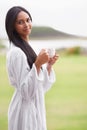 Taking in the tranquility of the moment. A beautiful young woman enjoying a cup of coffee while wearing a bathrobe. Royalty Free Stock Photo