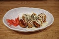 Takoyaki or Japanese octopus balls, serve on white plate on wooden counter. Royalty Free Stock Photo