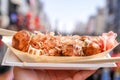 Takoyaki, Local Japanese octopus meat ball in the hand with blur cityscape, ready to eat