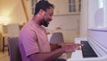 Talanted african american guy pianist playing piano and singing at home.