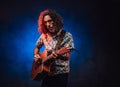 Talanted hispanic musician in a hawaiian shirt playing guitar on a dark