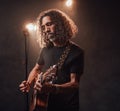 Talanted hispanic musician playing guitar in stage lights