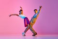 Talented, artisitc children, boy and girl in retro clothes dancing lindy hop against pink studio background in neon