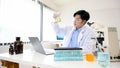 A talented Asian male scientist holding a beaker, doing a chemical experiment in the lab Royalty Free Stock Photo