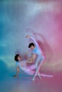 Talented ballet dancers in white attire performing artistic dance move in neon light against gradient studio background. Royalty Free Stock Photo