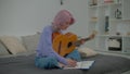 Talented charming female musician with guitar songwriting new song at home