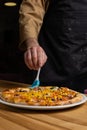 Talented chef carefully crafting a delicious pizza on a rustic wooden table