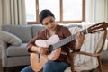 Happy young indian woman playing guitar at home. Royalty Free Stock Photo