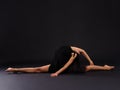 A talented girl sits in a string and bends back. On a black background. Royalty Free Stock Photo